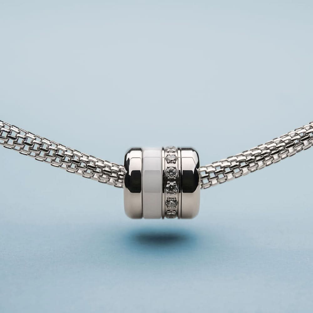 Edelstålscharm på armband: cylindriskt mittstycke med zirkonia och mörka ränder