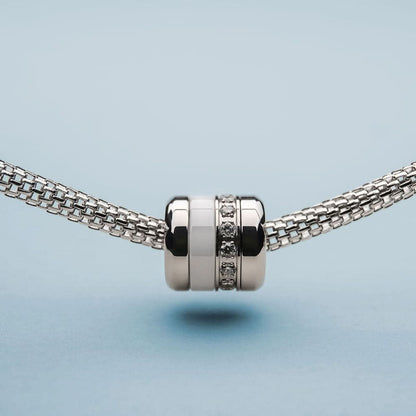 Edelstålscharm på armband: cylindriskt mittstycke med zirkonia och mörka ränder