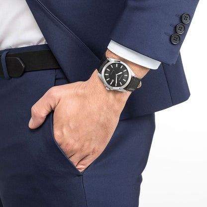 Herrarmbandsur på handleden med svart läderarmband och svart urtavla