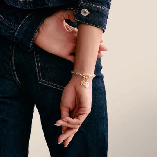 "Armband i silverfärgad länk på handleden med guldfärgat hänge"