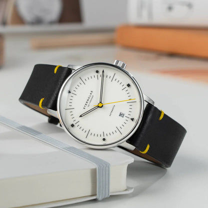 Sternglas Naos armbandsur på bok: vit urtavla, svart läderband med gula sömmar