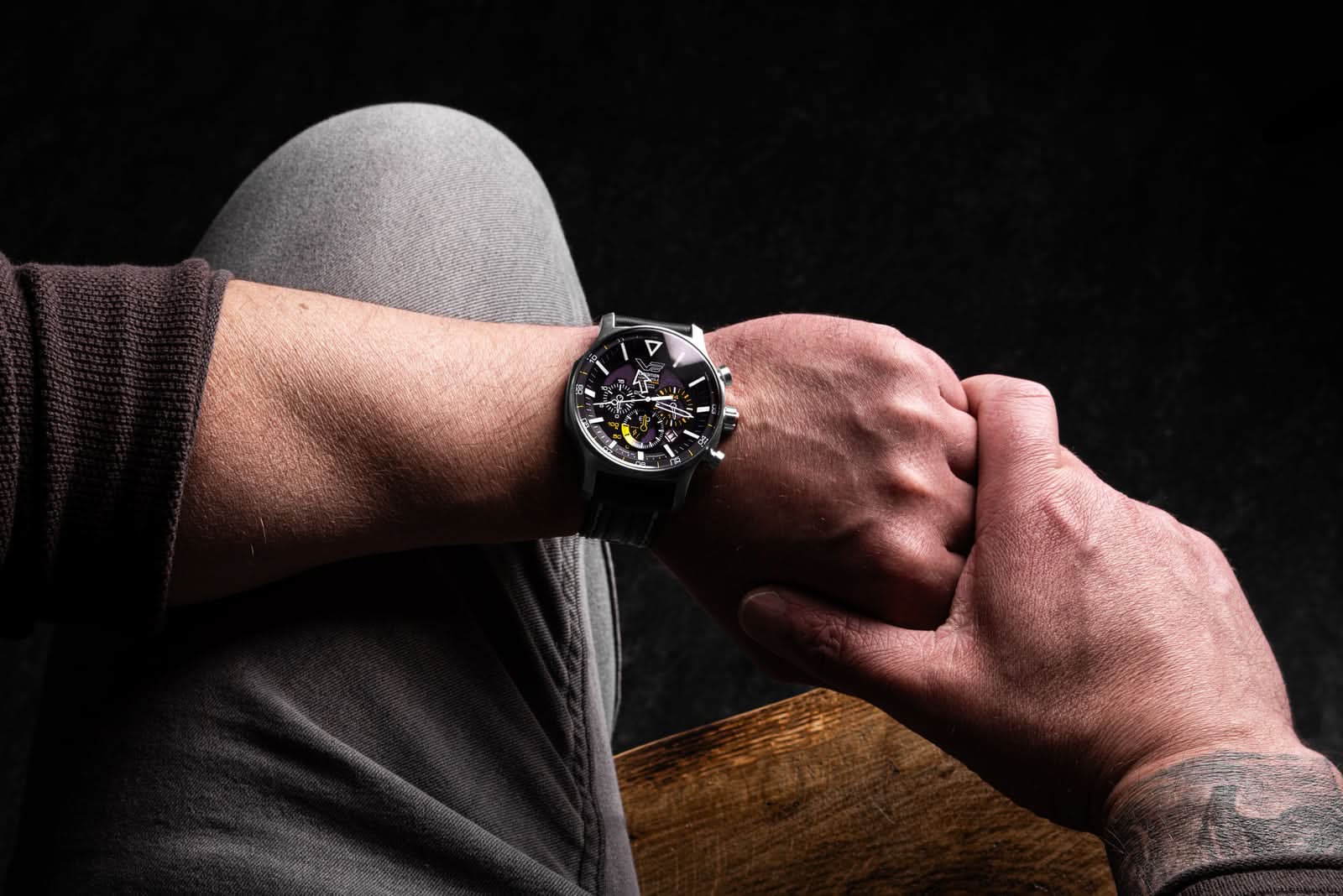 Herrklocka på handleden: svart läderarmband och mörk urtavla