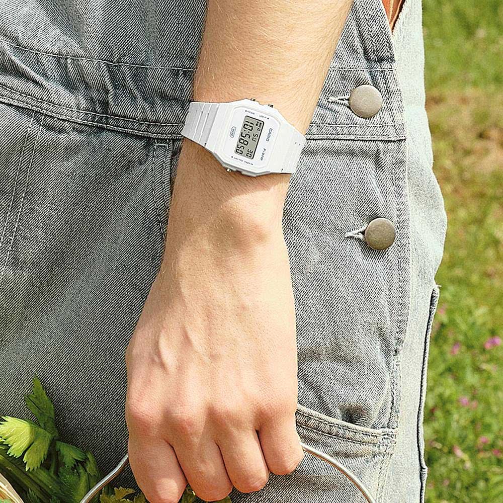 "Digital damklocka med vitt armband på handleden, display synlig över denim"