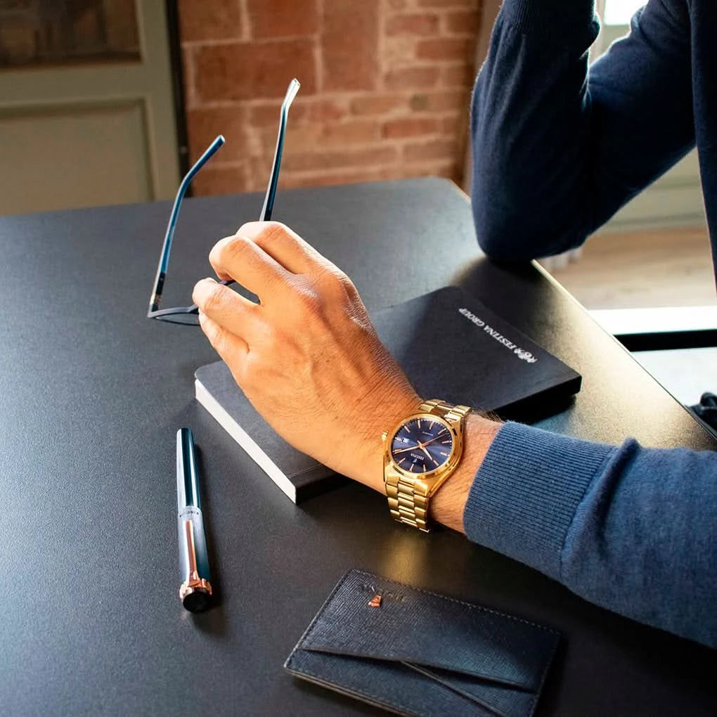 Festina herrklocka på handleden med blå urtavla och guldfärgat armband i rostfritt stål