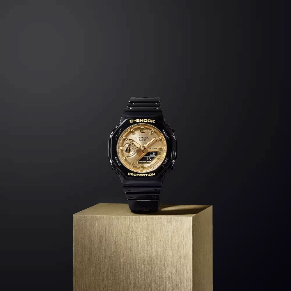 Casio G-Shock herrklocka på piedestal: svart armband och guldfärgad urtavla, runt boett