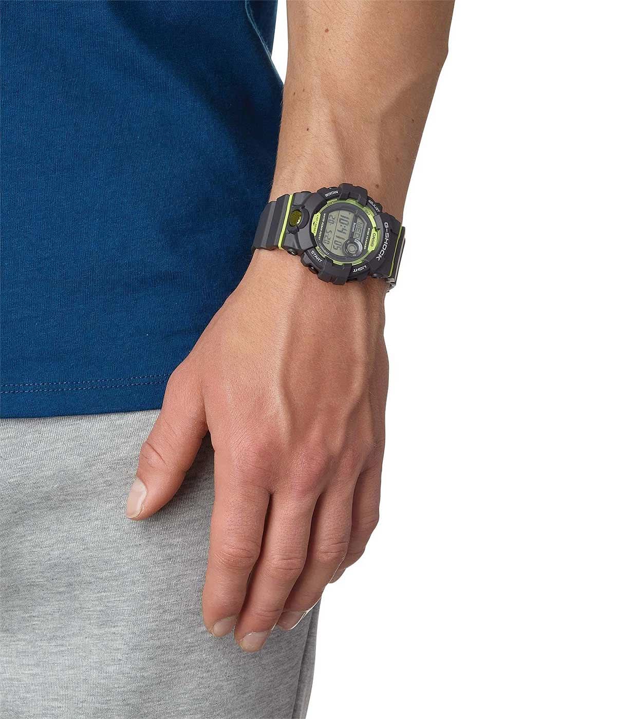 G-Shock herrklocka på handleden, svart armband med gröna detaljer och rund display