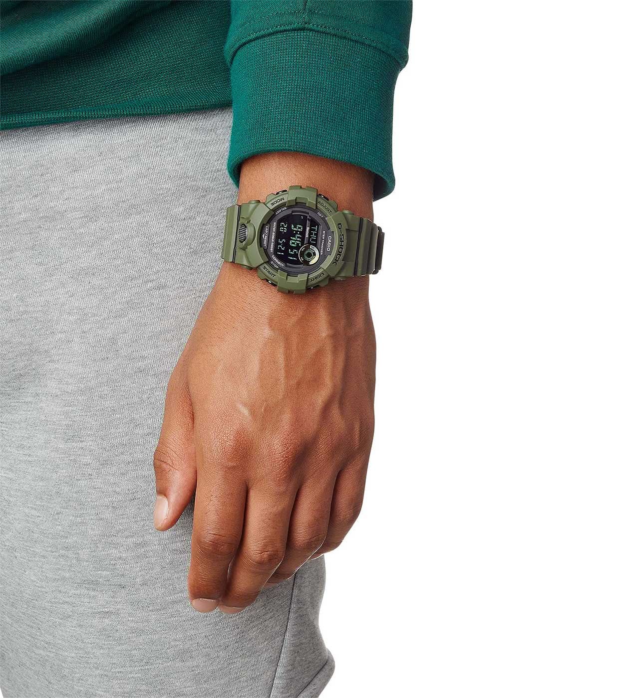 Digital herrklocka på handleden med grönt boett och gummiband