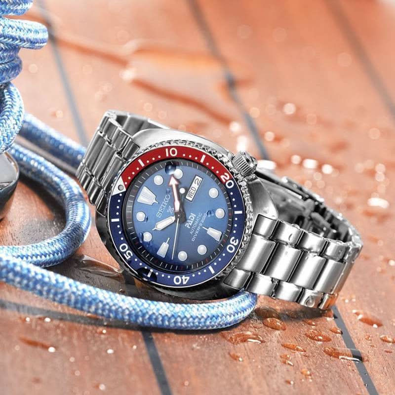 Seiko Prospex dykarur med blå urtavla, röd bezel och armband i rostfritt stål.