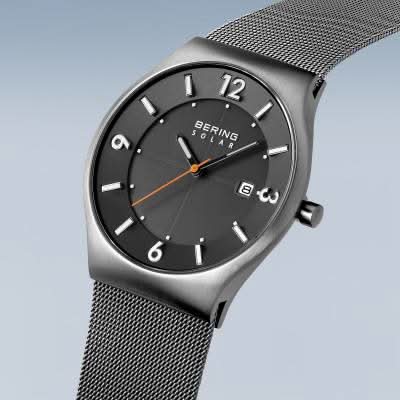 Herrklocka med solcellsdrivning, svart urtavla, indexmarkeringar och krona åt höger, milanesarmband