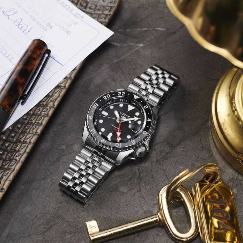 Seiko herrklocka på underlag: silverfärgat armband i rostfritt stål, svart urtavla med GMT