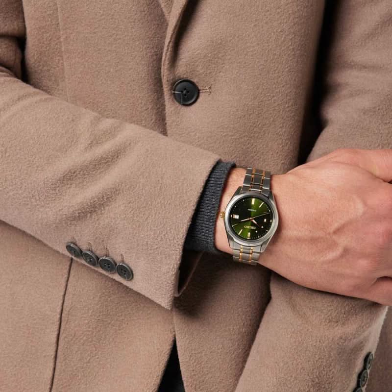 Herrklocka på handleden med grön urtavla och tvåfärgat metallarmband