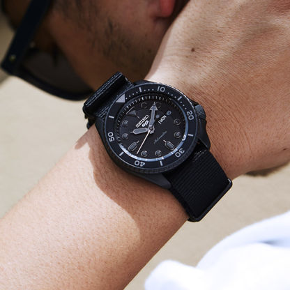 "Seiko 5 Sports herrklocka på handleden, svart textilarmband och svart urtavla"
