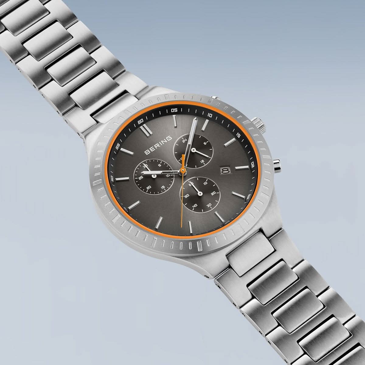 Herrarmbandsur i snedbild: titanarmband, svart urtavla med orange accenter