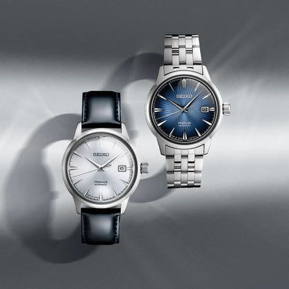 "Två herrur från SEIKO: blå urtavla med metallarmband, ljus med läderarmband"