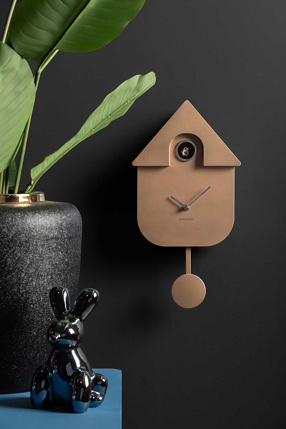 beige plastväggklocka i husdesign med pendel och runt fönster på framsidan