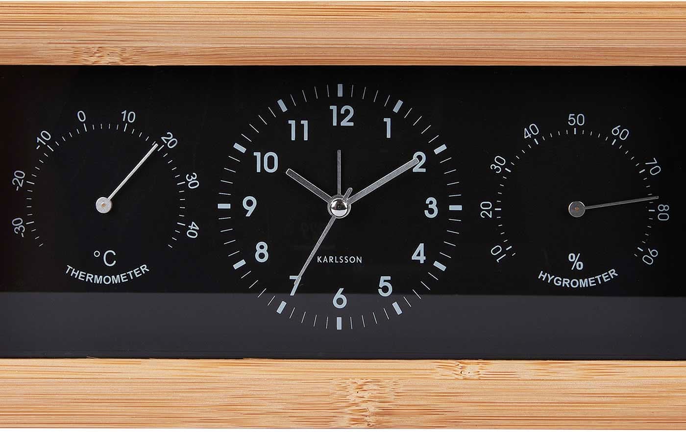 Analog väckarklocka med bamburam i närbild, svart urtavla med temperatur- och fuktskala