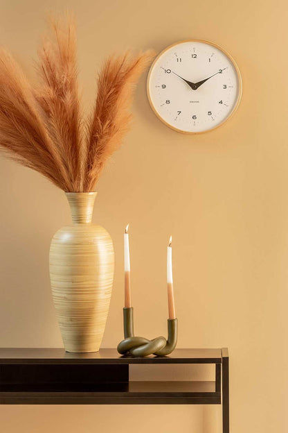 Väggklocka på väggen med beige träram, vit urtavla och svarta visare