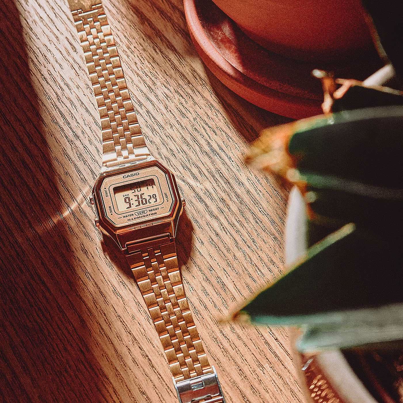Casio damklocka med metallfärgat metallarmband och digital display på träplatta