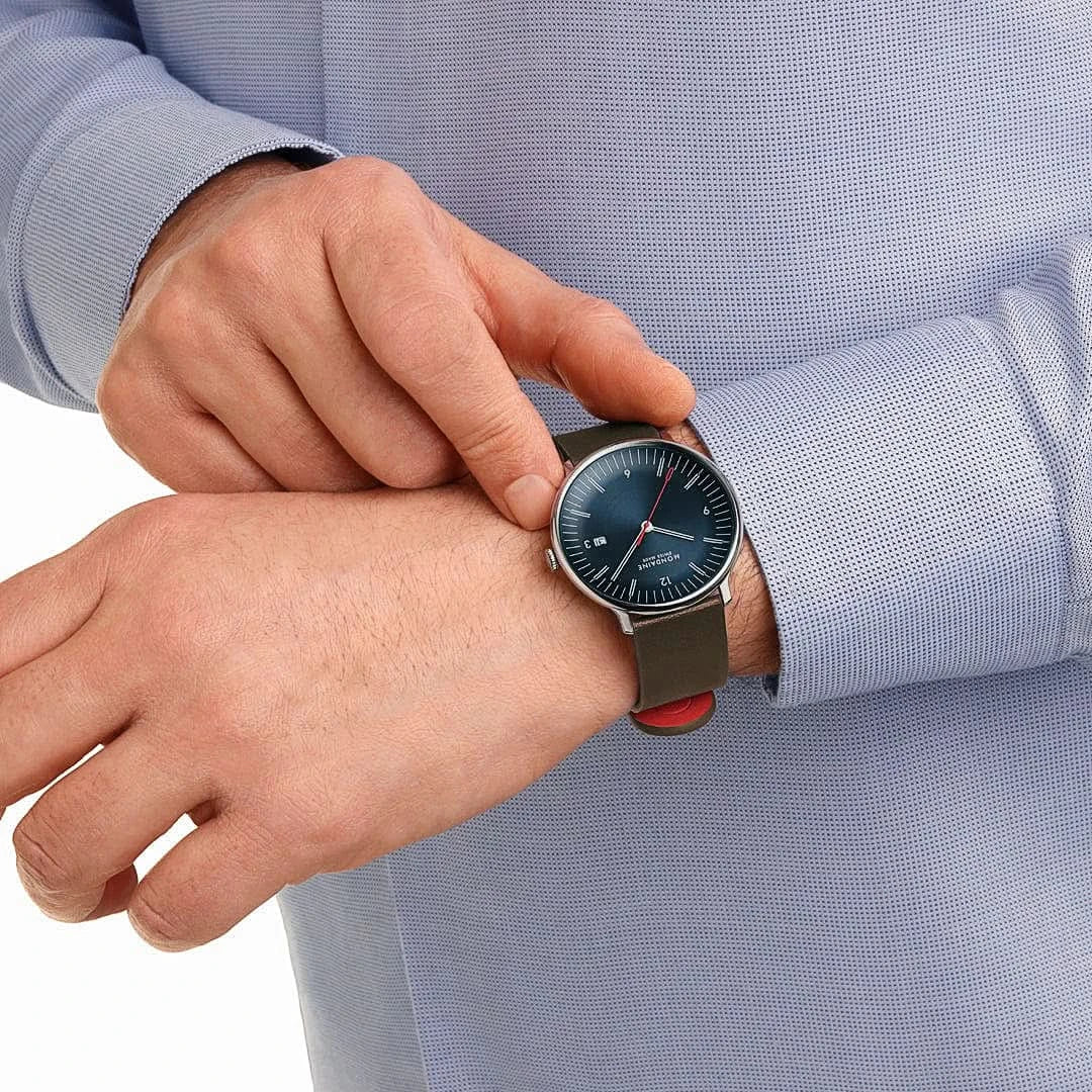 Herrklocka på handleden med brunt armband och mörkblå urtavla