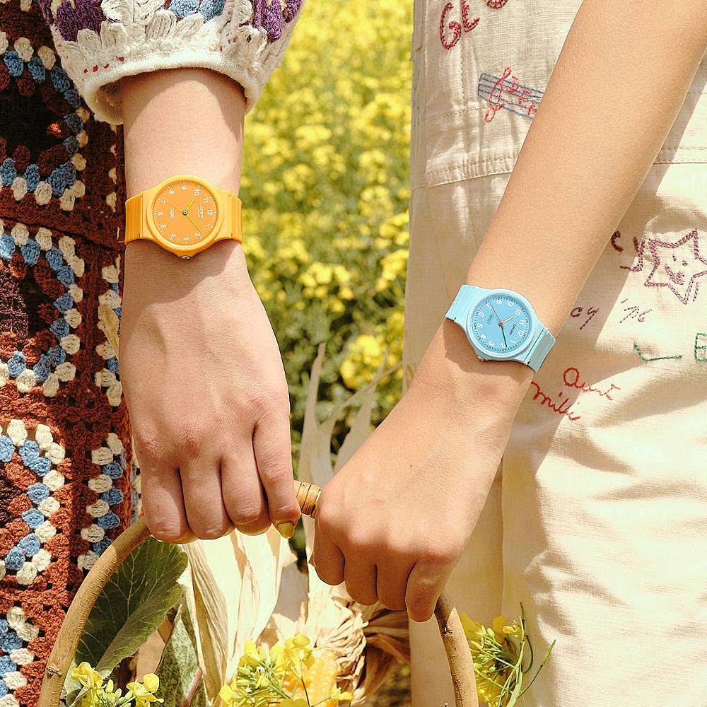 Damklocka på handleden med orange armband; en till med blått armband