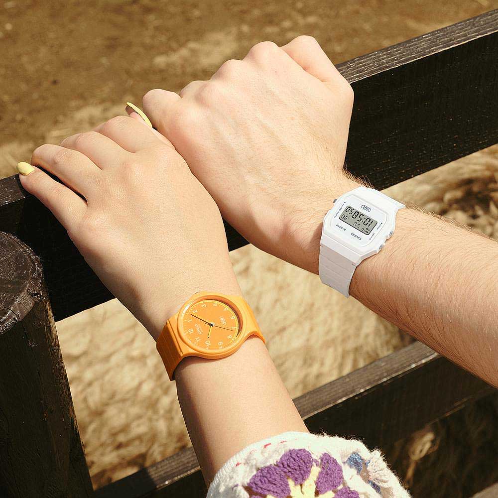 Damklocka med orange armband och rund urtavla på handleden