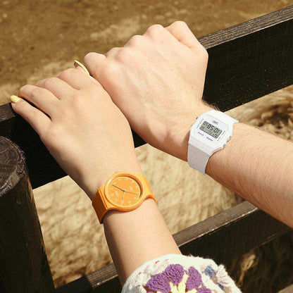 Damklocka med orange armband och rund urtavla på handleden