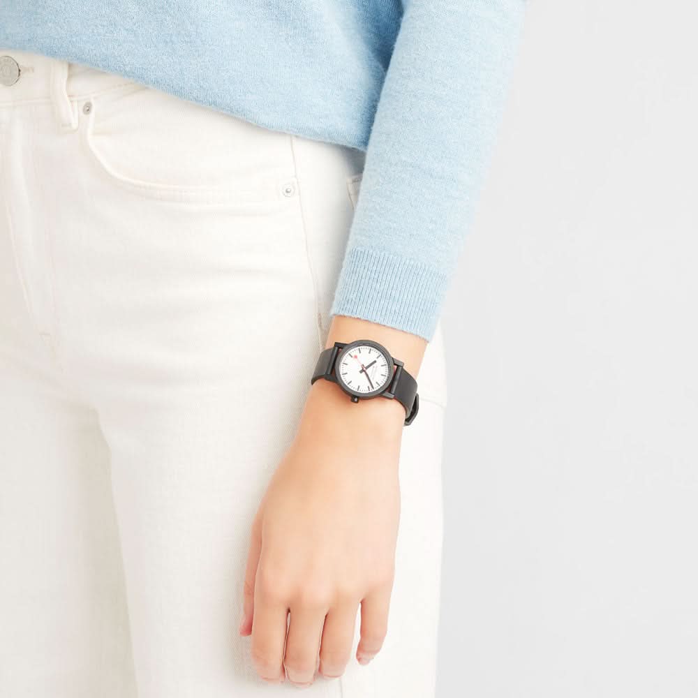 Damklocka på handleden: svart armband och vit urtavla med orange accenter