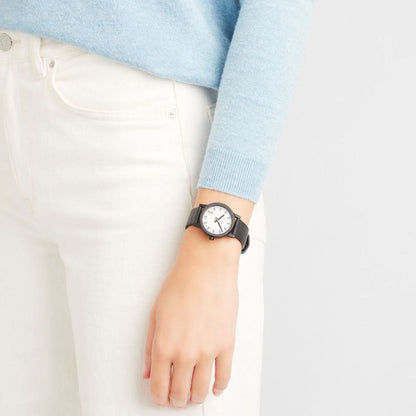 Damklocka på handleden: svart armband och vit urtavla med orange accenter