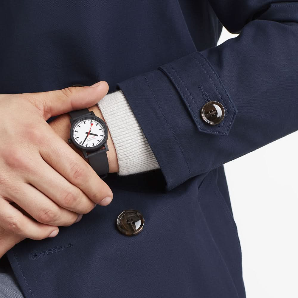 "Damklocka på handleden under blå ärm, svart armband och vit urtavla"