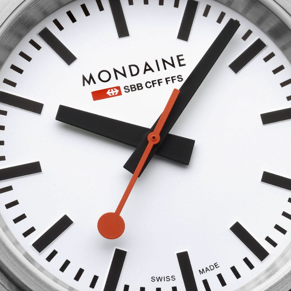 Urtavla med MONDAINE, orange sekundvisare och svarta minutmarkeringar