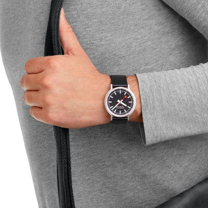 "Mondaine Stop2Go-klocka på handleden med svart läderarmband och svart urtavla"