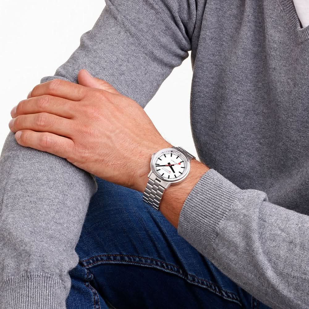 Mondaine herrklocka på handleden, frontvy med silverfärgat armband i rostfritt stål