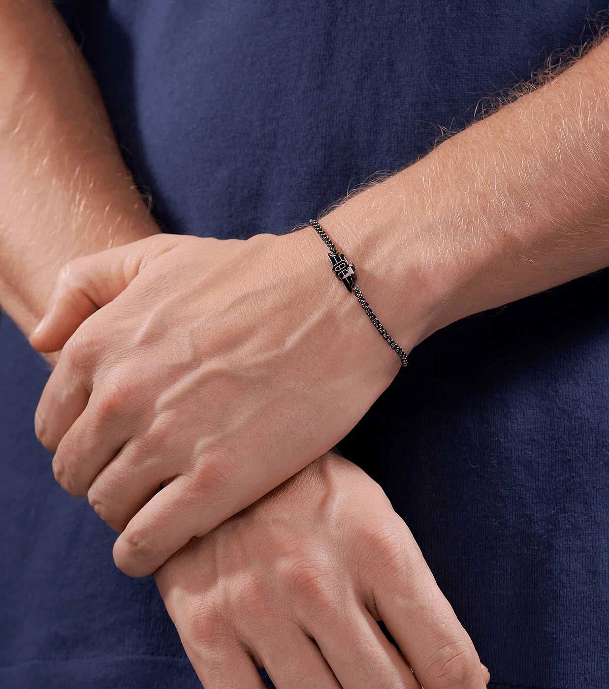 "Grått armband runt handleden med fin länkkedja och litet logohänge"