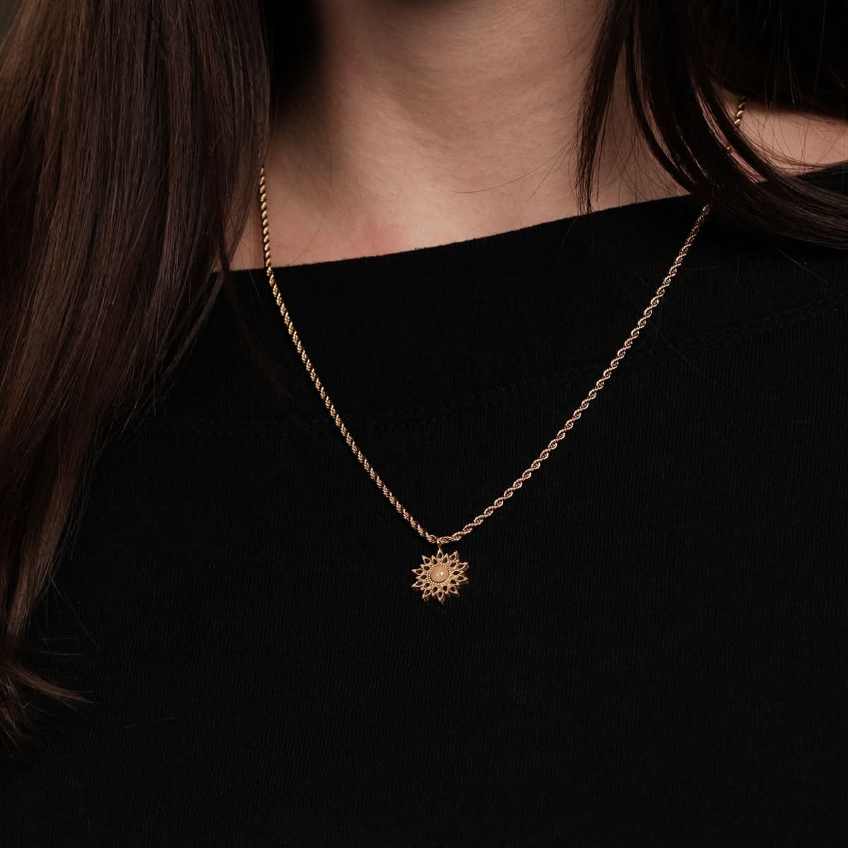 Gyllene halsband med fin kedja och litet solhänge vid halsen