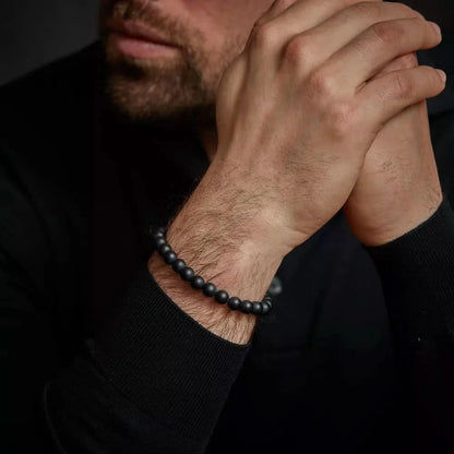 Armband med svarta pärlor runt handleden, svart stålspänne
