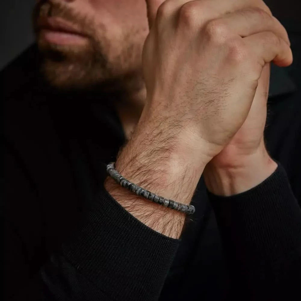 Armband av gråa naturstenspärlor på handleden med litet spänne i rostfritt stål