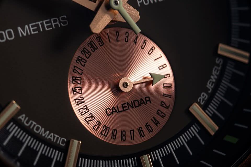 Herrklocka med kopparfärgad delurtavla och "CALENDAR"-märkning