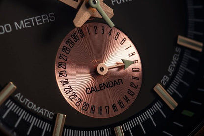 Herrklocka med kopparfärgad delurtavla och "CALENDAR"-märkning