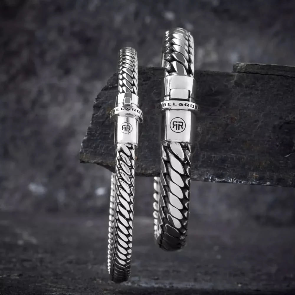 Silverfärgat armband med flätad länkdesign och spänne med GR-logotyp