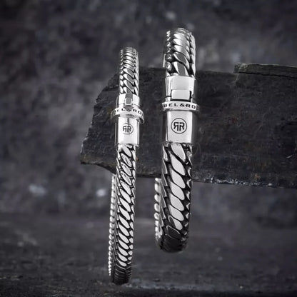 Silverfärgat armband med flätad länkdesign och spänne med GR-logotyp