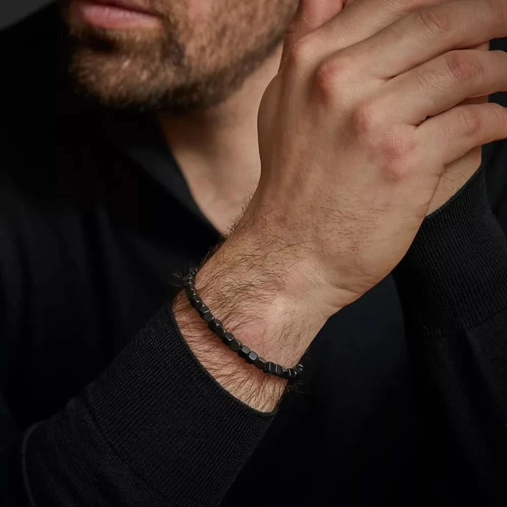 Armband runt handleden med mörka pärlor och litet metallspänne