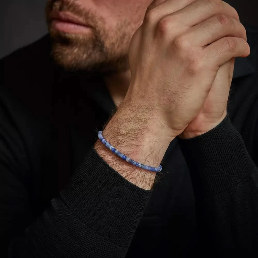 Armband med skivor av blå ädelstenar runt handleden med lås i rostfritt stål