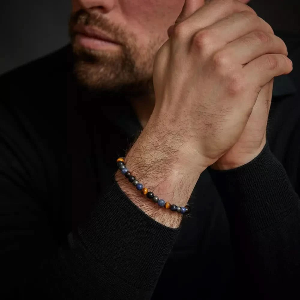 Armband runt handleden med blå och guldfärgade pärlor samt gråa hematitstenar, REBEL&ROSE-lås
