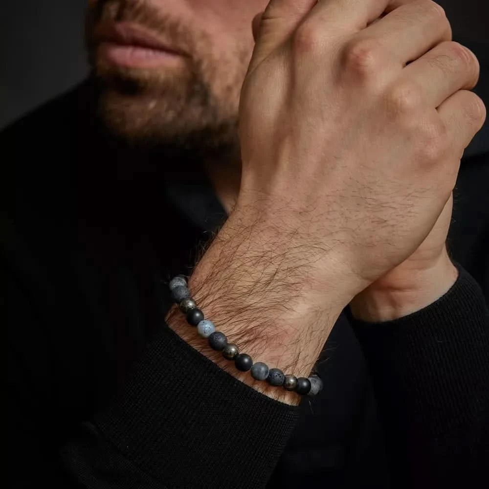 Armband med mörka stenpärlor på handleden, grått rostfritt stållås