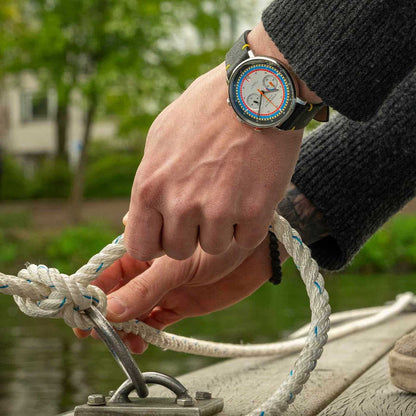 Herrklocka på handleden: svart läderarmband, silverfärgad urtavla med färgglada markeringar