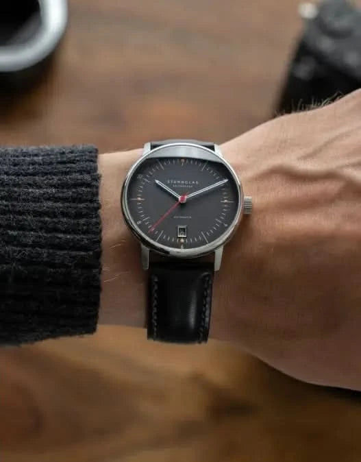 Herrarmbandsur på handleden med svart läderarmband och mörk urtavla