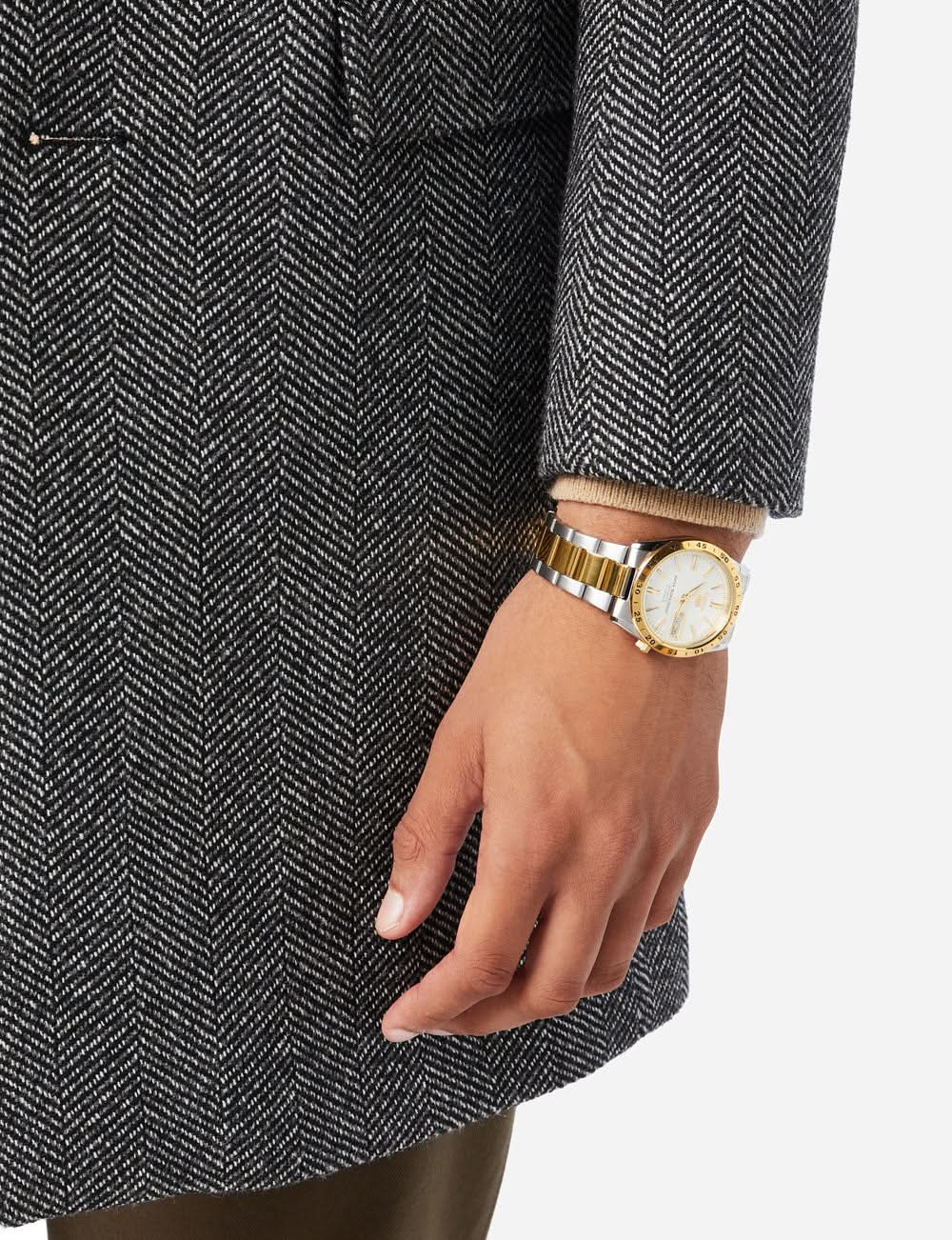 Bicolore herrklocka på handleden, silverfärgat armband med gulddetaljer, rund urtavla