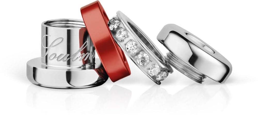 Charm i rostfritt stål i detalj: silverringar, rött band och zirkoniastenar