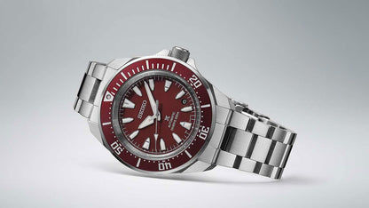 Seiko herrklocka med röd urtavla och röd bezel, armband i rostfritt stål, sidovy