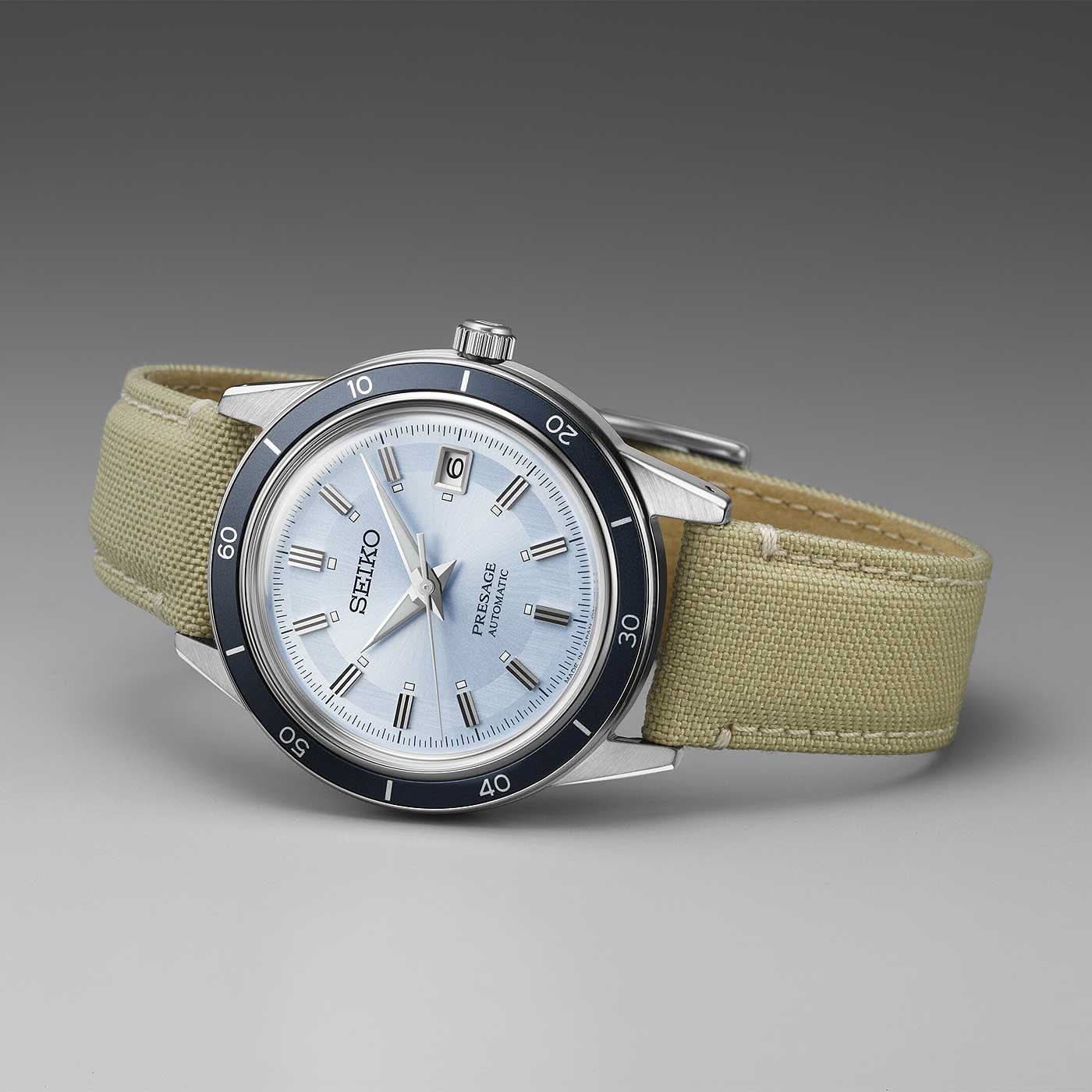 Herrklocka med beige läderarmband, silverfärgad urtavla, blå vridring och indexmarkeringar